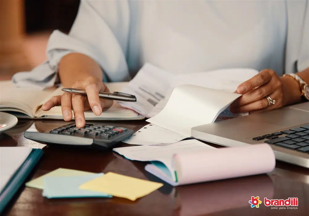 Mulher segurando papéis e digitando em calculadora