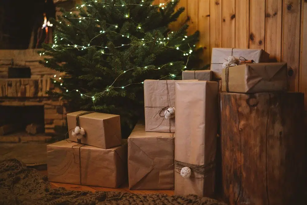 presentes embalados no chão ao lado da árvore de natal