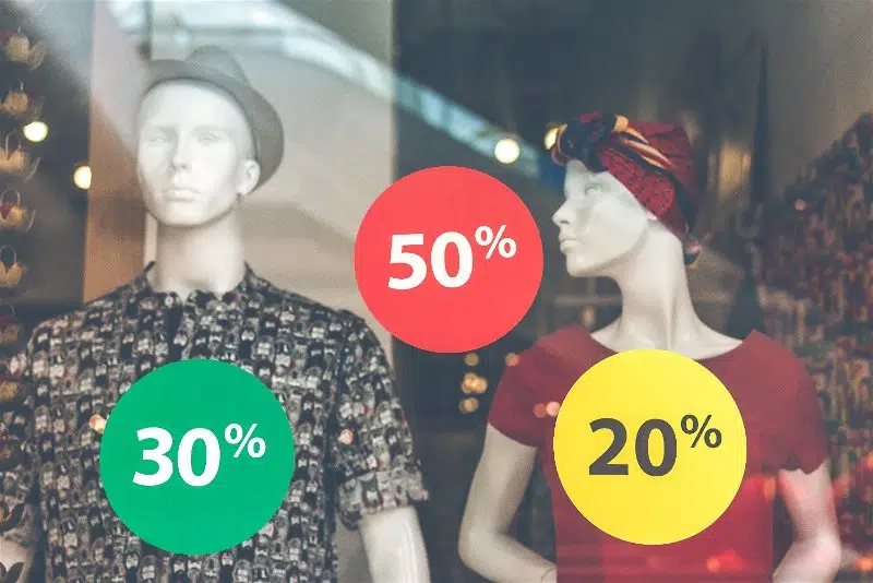 vitrine de uma loja de roupas com adesivos de desconto colados na parede