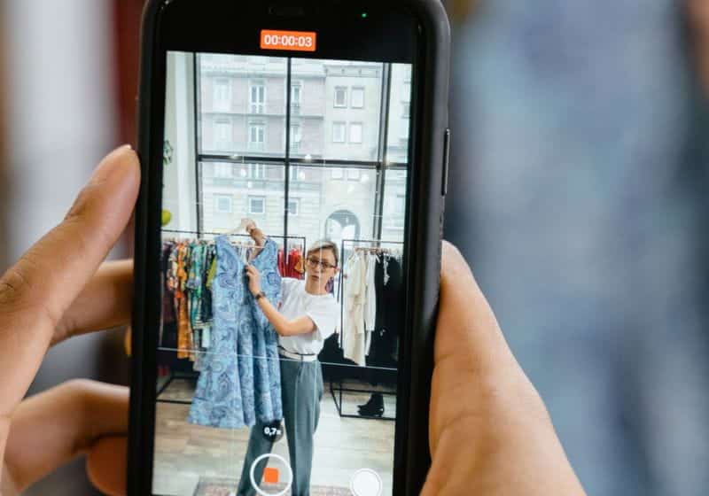 foto de uma tela do celular que estava gravando um vídeo de uma molhar mostrando algumas roupas em uma loja