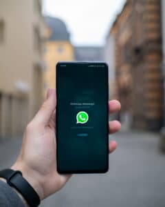 mão segurando um celular com o WhatsApp aberto