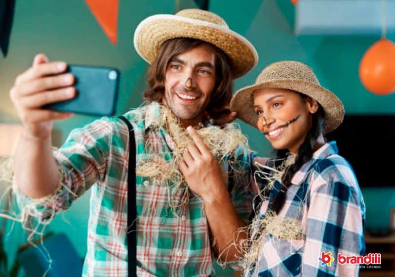 casal vestido com roupas típicas de festa junina tirando uma selfie