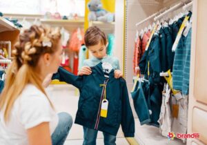 menino escolhendo uma jaqueta em uma loja de roupas com a sua mãe