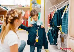 menino escolhendo uma jaqueta em uma loja de roupas com a sua mãe