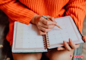 mulher sentada com um caderno em seu colo e um lápis na mão verificando o calendário