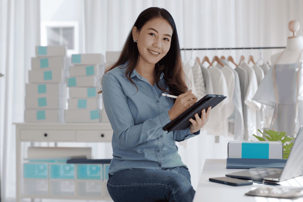 Mulher sorridente escrevendo em tablet em loja de moda