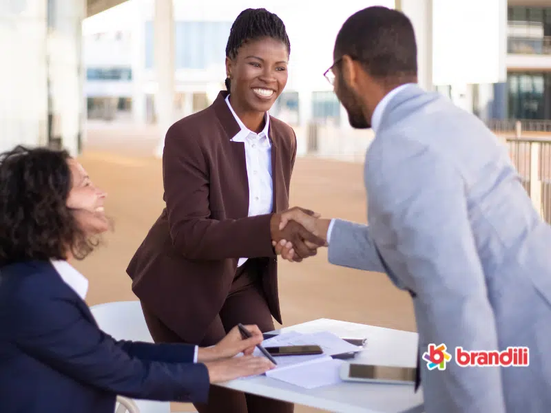 Mulher e homem empresários apertam as mãos sorrindo
