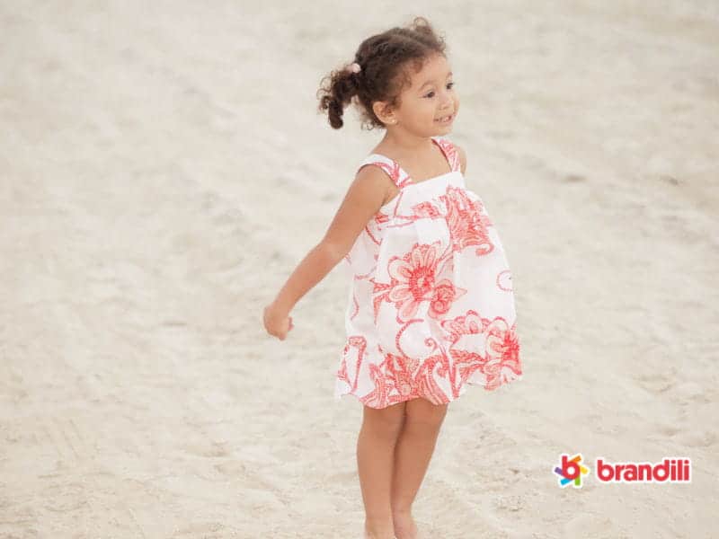 Menina na praia com vestido infantil florido de linho