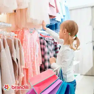 garota com sacolas de compras olhando para as de roupas em cabideiro