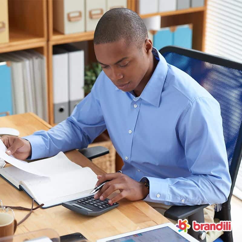 homem fazendo calculos utilizando uma calculadora sobre uma mesa de escritorio