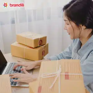 mulher digitando em um notebook com caixas sobre a mesa