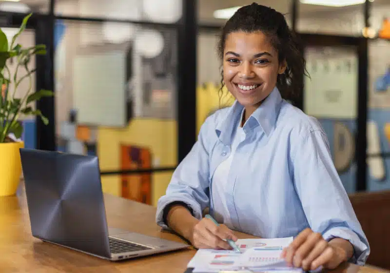 mulher sorridente empreendedora planejando com notebook e papeis 