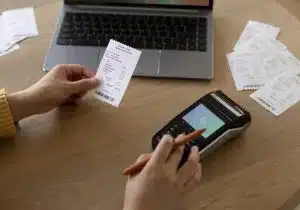 Mãos segurando recibo e máquina de pagamento