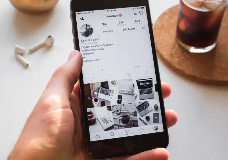 vista de cima de mão de homem segurando celular na pagina do Instagram 