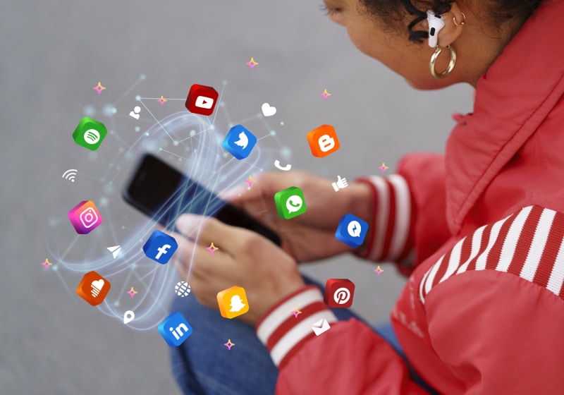 mulher de angulo de cima segurando smartphone com ícones de redes sociais interativas saindo do celular