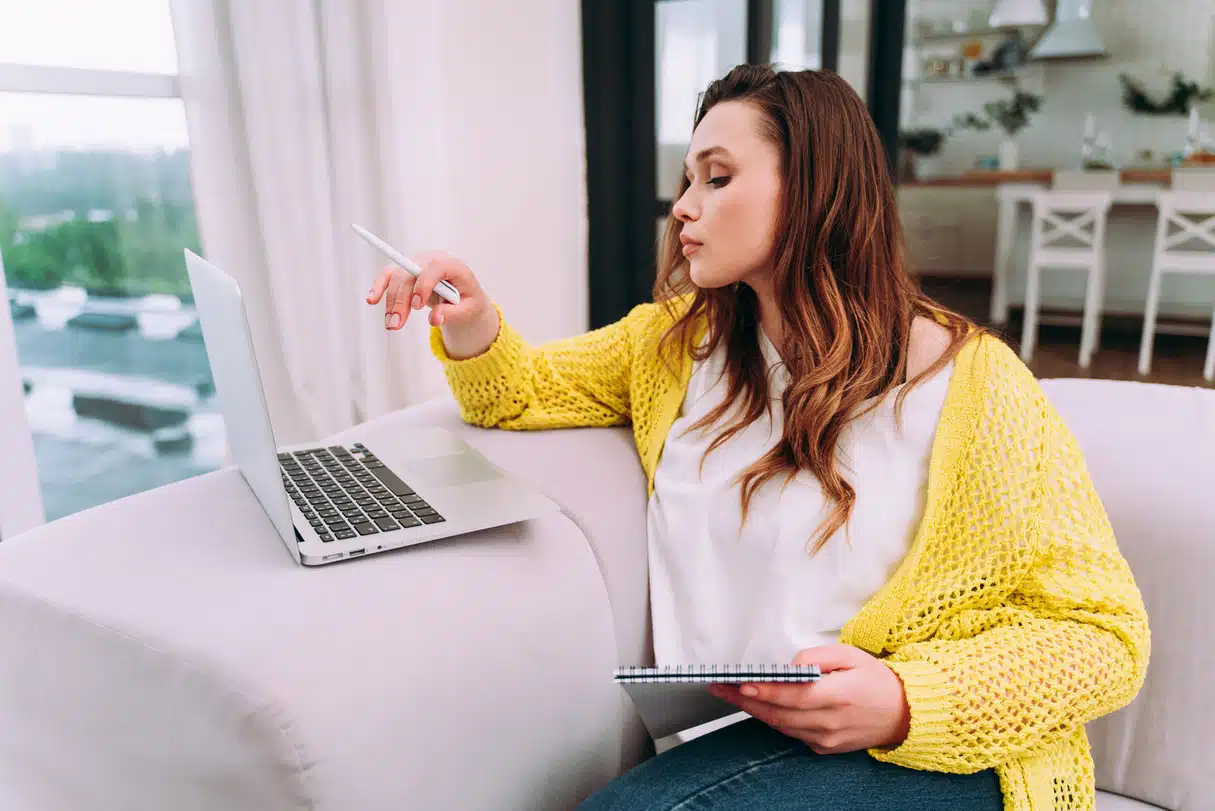 mulher sentada no sofá mechendo no computador