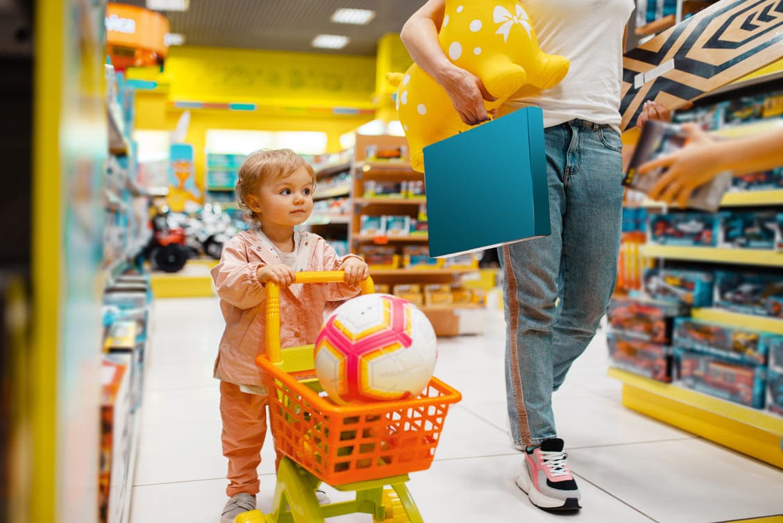Criança em loja empurrando pequeno carrinho de supermercado 