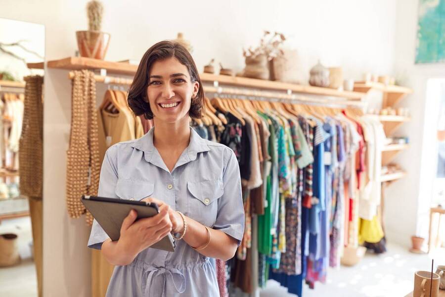 microempreendedora individual posa para a foto em sua loja de roupas