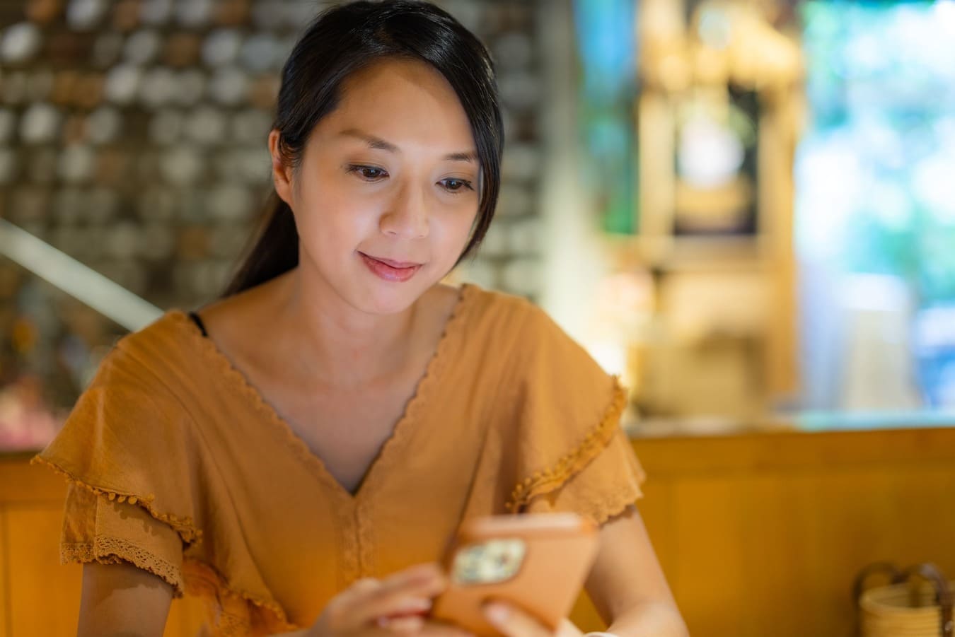mulher sentada em um restaurante mexendo no celular