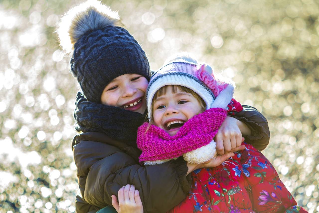  duas crianças felizes, menino e menina brincando ao ar livre, com acessórios de frio