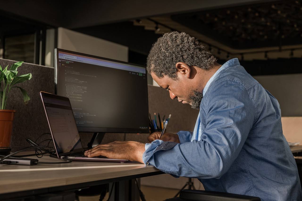 homem negro escrevendo linhas de código no PC desktop com