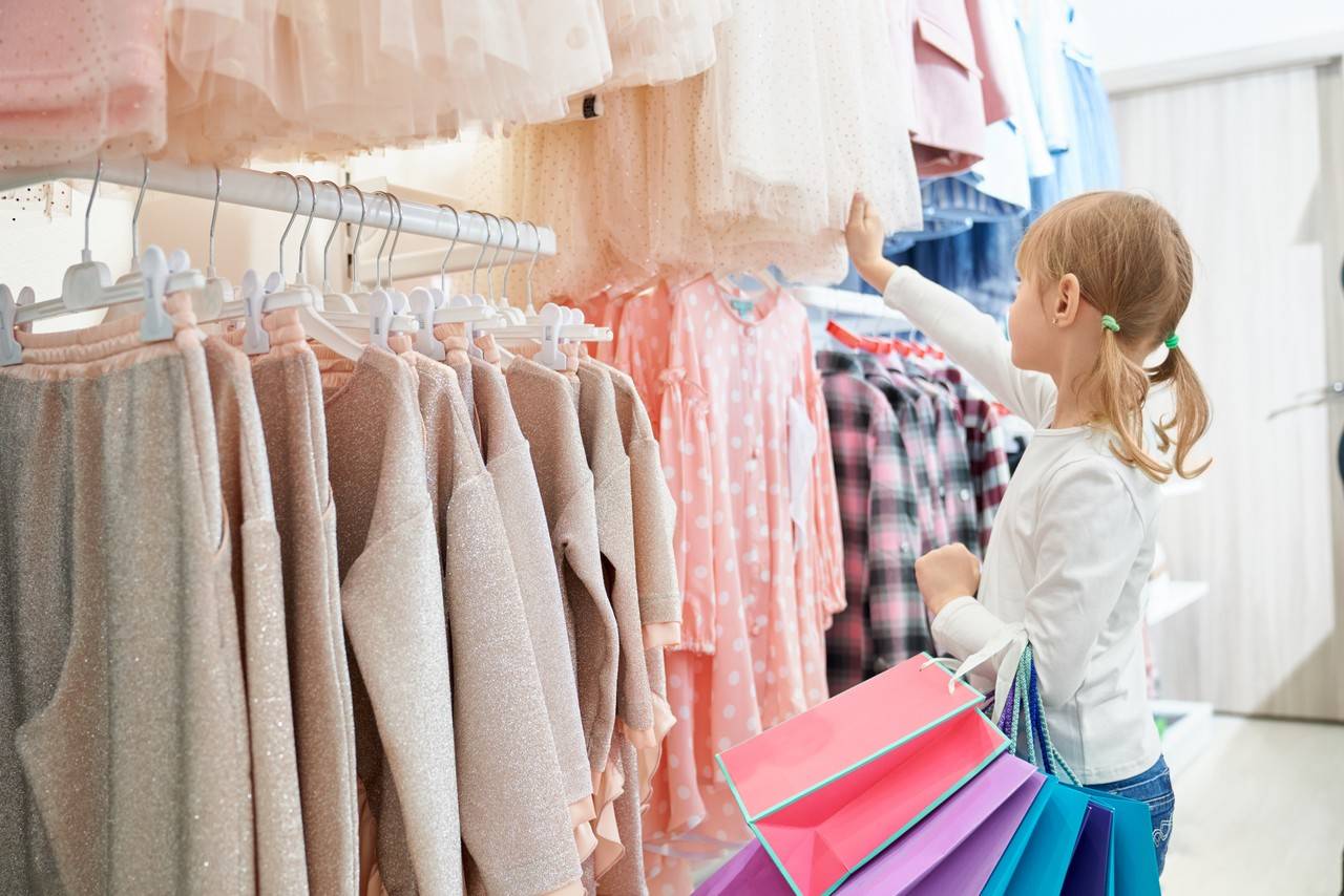 menininha conferindo roupas infantis nas araras