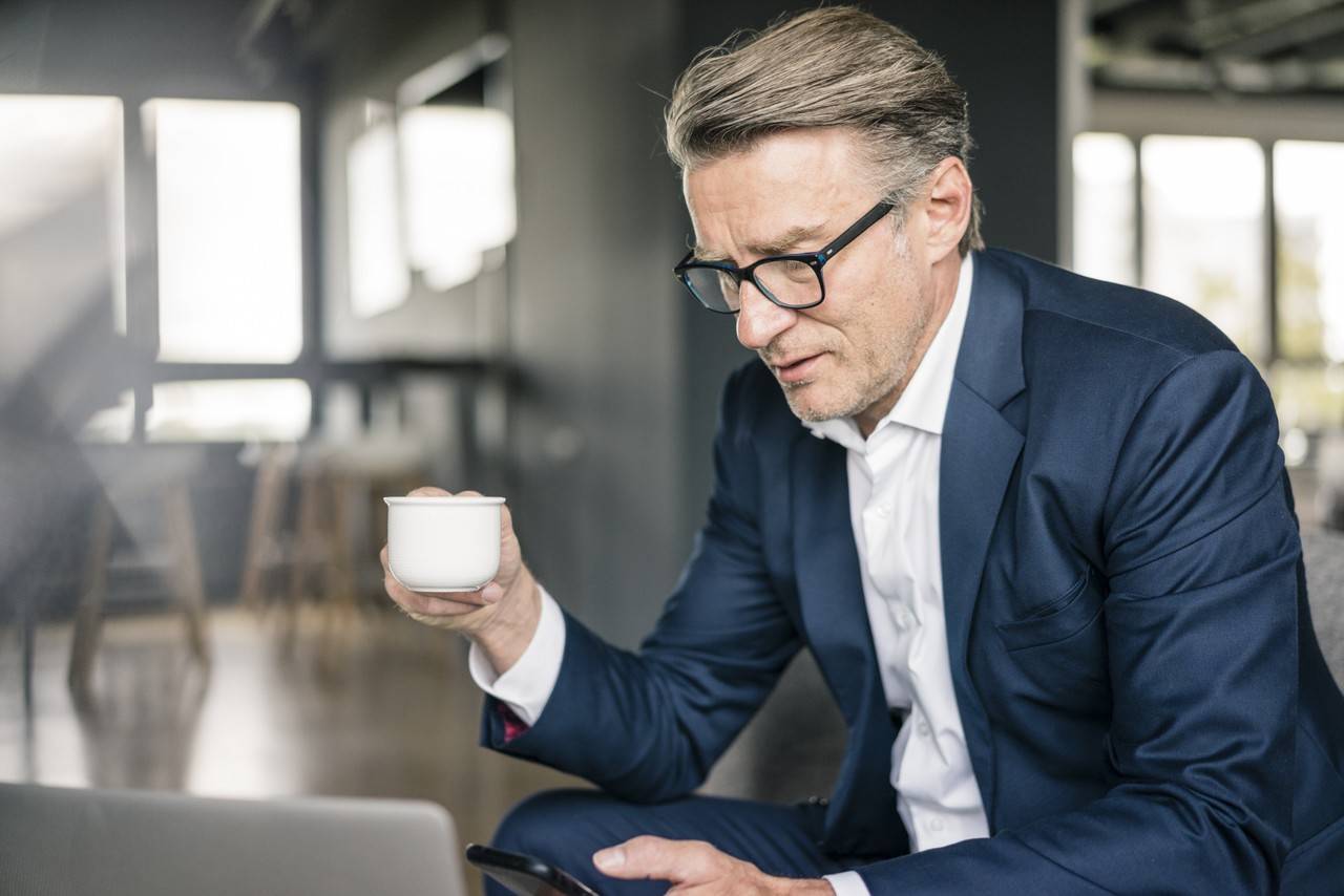 homem tomando café enquanto olha o whatsapp