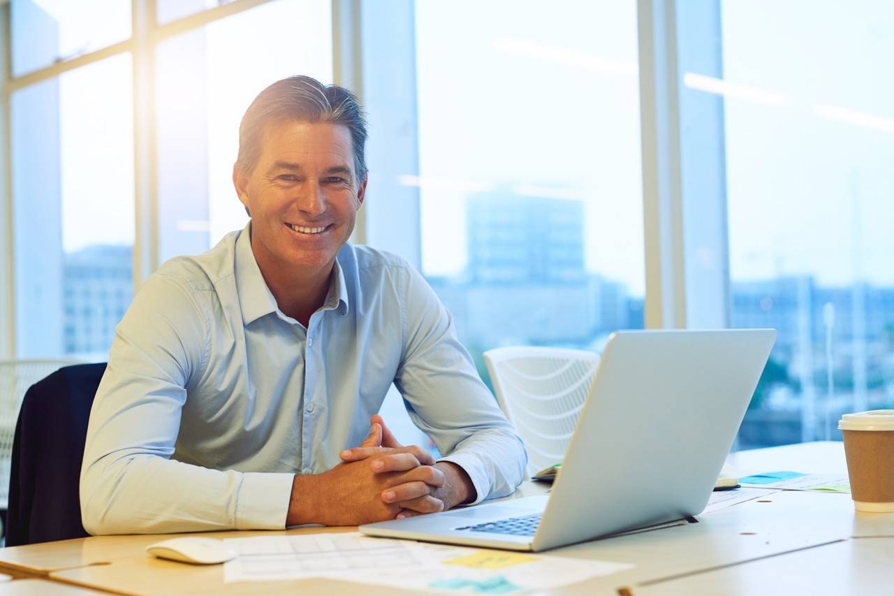 homem sorrindo em frente notebook