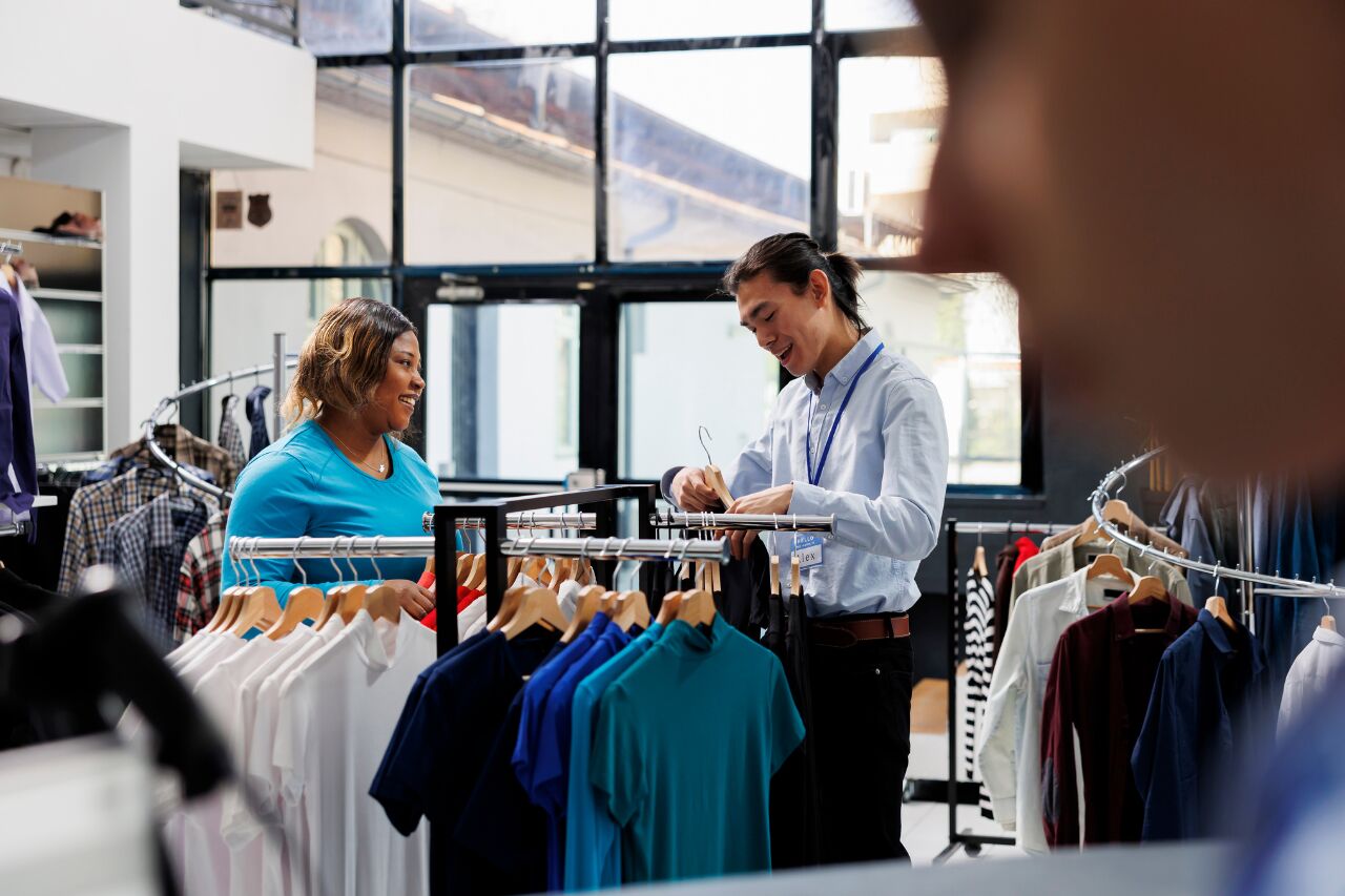 Cliente sorridente atende vendedor em loja de roupas.